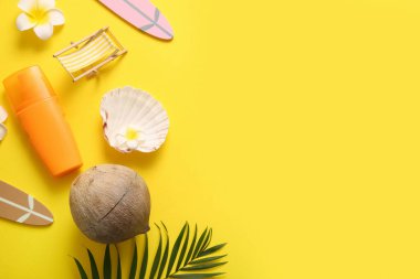 Hindistan cevizli yaz kompozisyonu, bir şişe güneş kremi ve sarı arka planda dekoratif iskemle.