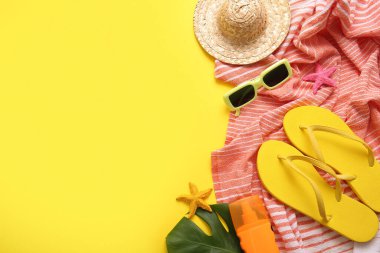 Sarı arka planda plaj havlusu ve aksesuarlı yaz kompozisyonu