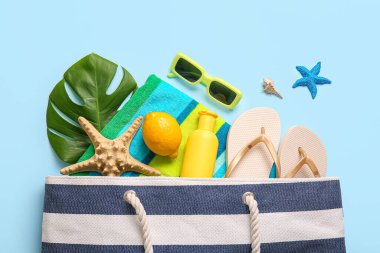 Limonlu, yeşil yapraklı ve mavi arka planda plaj aksesuarlı yaz kompozisyonu