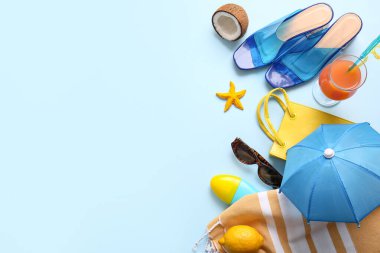 Meyveli yaz kompozisyonu, bir bardak kokteyl ve mavi arka planda plaj aksesuarları