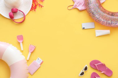 Sarı zemin üzerinde şişirilebilir halkalar, cep telefonu ve plaj aksesuarlarından yapılmış çerçeve