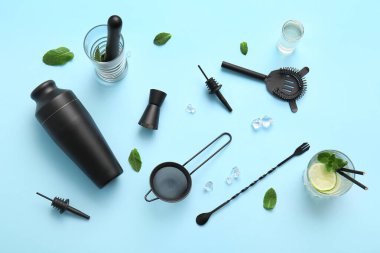 Mavi arka planda barmen aletleri, nane yaprakları ve buz küpleriyle kompozisyon