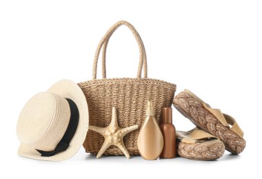 Hasır çanta, güneş kremi şişeleri ve beyaz arka planda izole edilmiş plaj aksesuarları.