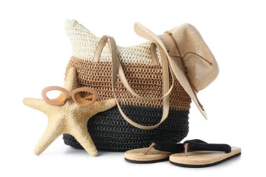 Beyaz arka planda deniz yıldızı ve aksesuarlı plaj çantası, yakın plan.