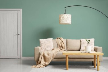 Gri kanepesi, ahşap masası ve lambası olan şık bir oturma odası.