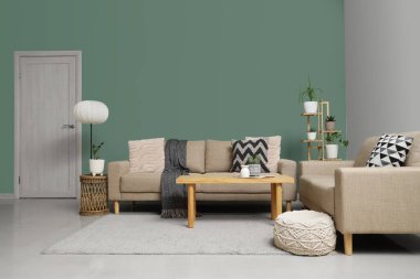 Oturma odasının içinde rahat koltuklar, puf ve masa.