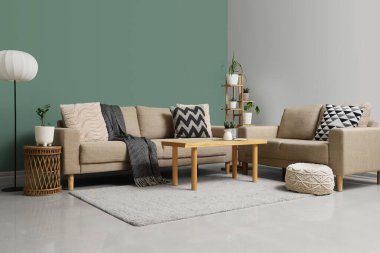 Oturma odasının içinde rahat koltuklar, puf ve masa.