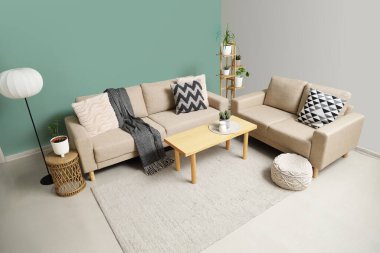 Oturma odasının içinde rahat koltuklar, puf ve masa.