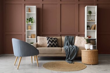 Oturma odasının içinde rahat bir kanepe, raf üniteleri ve kahverengi duvarın yanındaki masa.