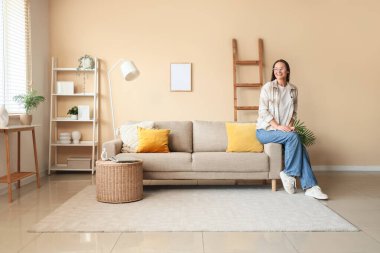 Evde kanepede oturan genç kadın