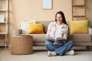 Evde dinlenirken dergi okuyan genç bir kadın.