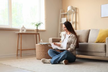 Evde dinlenirken dergi okuyan genç bir kadın.