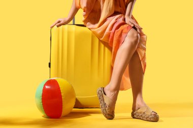 Çantalı genç bir kadın ve sarı arka planda şişme top.