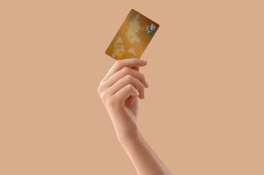 Bej arka planda kredi kartı olan bir kadın.