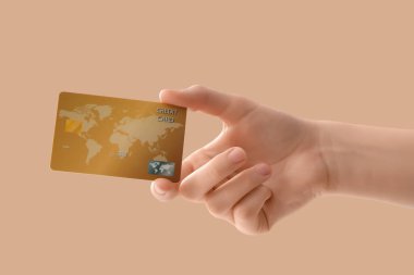 Bej arka planda kredi kartı olan bir kadın.