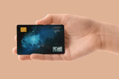 Bej arka planda kredi kartı olan bir kadın, yakın plan.