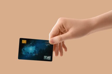 Bej arka planda kredi kartı olan bir kadın.