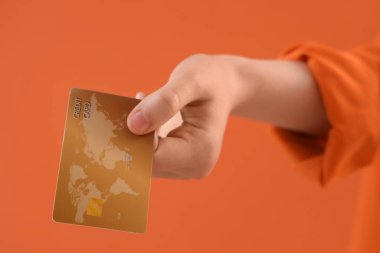 Turuncu arka planda kredi kartı olan bir kadın, yakın plan.