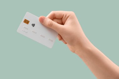 Hafif turkuaz arka planda kredi kartı olan bir kadın, yakın plan.