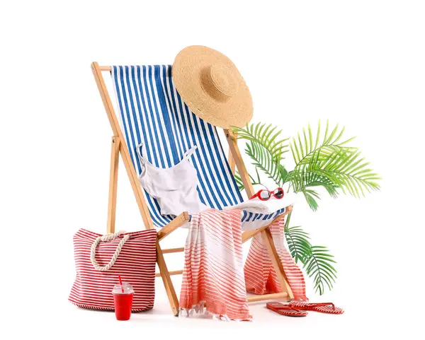 Çizgili iskemle, mayo, plaj aksesuarları ve beyaz arka planda izole edilmiş meyve suyu dolu plastik bardak.