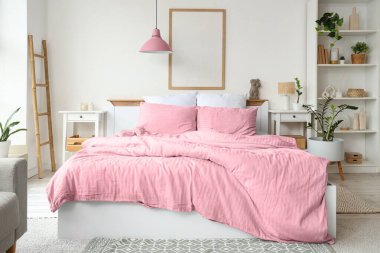 Konforlu yatağı, raf ünitesi ve çiçekleri olan hafif yatak odasının içi.