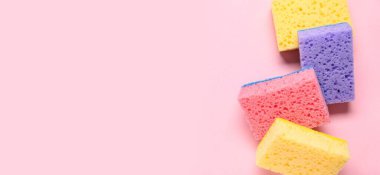 Süngerler pembe arkaplanda metin için boşluk ile temizleniyor