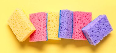 Sarı arka planda birçok temizlik süngeri, üst görünüm