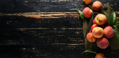 Koyu ahşap zemin üzerinde bir sepet taze şeftali, metin için yer, üst görünüm