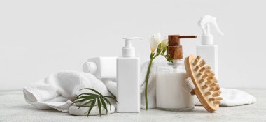 Kozmetik ürünler, masaj fırçası, temiz havlu ve çiçek.