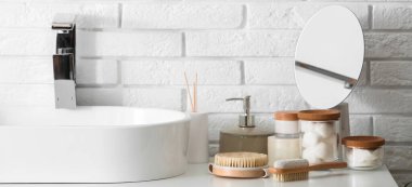 Masaj vücut fırçaları ve kozmetik ürünleri lavabonun yanındaki masada.