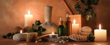 Mum yakma, kozmetik ürünleri şişeleri ve bej kaplama arka planda masaj malzemeleri, yakın çekim