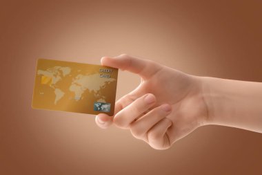 Kahverengi arka planda kredi kartı olan bir el.