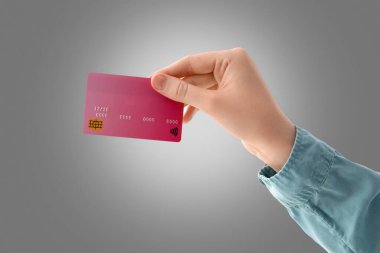 Gri arka planda kredi kartı olan el.