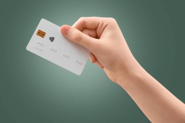 Yeşil arka planda kredi kartı olan el.