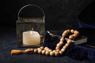 Müslüman lambası yanan mum, dua boncukları ve koyu arkaplanda Kur 'an