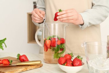 Kadın mutfakta çilekli limonata hazırlıyor.