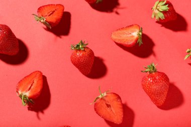 Kırmızı arka planda bir sürü taze çilek