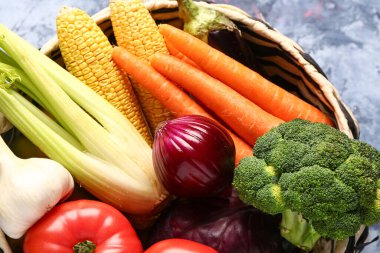 Mavi arka planda farklı taze sebzelerle hasır kase, yakın plan.