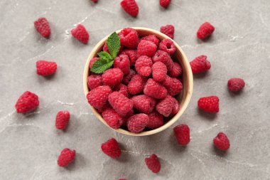 Gri arka planda taze ahududu ve naneli kase, yakın plan.