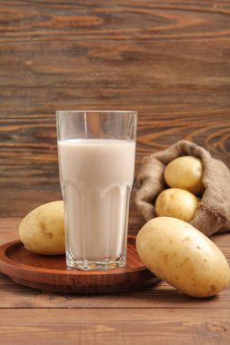 Tahta arka planda bir bardak lezzetli patates sütü.