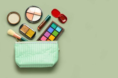 Yeşil arka planda farklı dekoratif kozmetik ürünlere sahip çanta