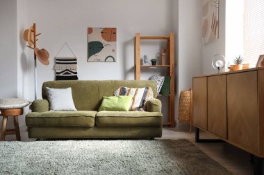 Rahat oturma odasının içinde yastıklar olan yeşil bir kanepe.