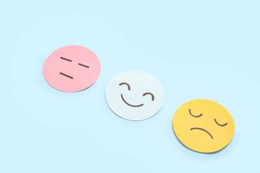 Mavi arka planda farklı duyguları olan kağıt yüzler. Ruh Sağlığı Günü