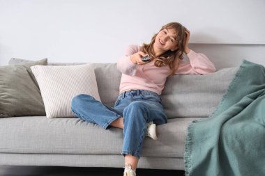 Genç kadın evde kanepede televizyon izlerken