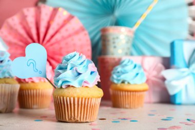 Soru işaretli leziz kekler, hediye kutuları ve pembe arka plandaki süslemeler. Cinsiyet ortaya çıkan parti kavramı