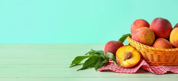 Корзина свежих персиков на столе на цветном фоне с местом для текста 