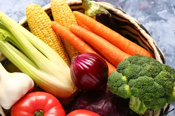 Mavi arka planda farklı taze sebzelerle hasır kase, yakın plan.