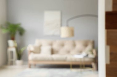 Modern oturma odasının bulanık manzarası rahat beyaz kanepe, sehpa ve standart lamba.