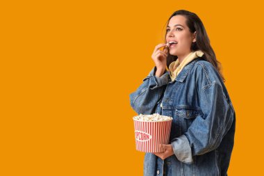 Sarı arka planda patlamış mısır yiyen güzel genç bir kadın.