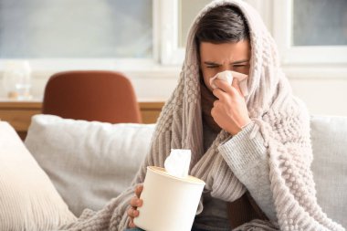 Ekoseli ve peçeteli hasta çocuk evde hapşırıyor.